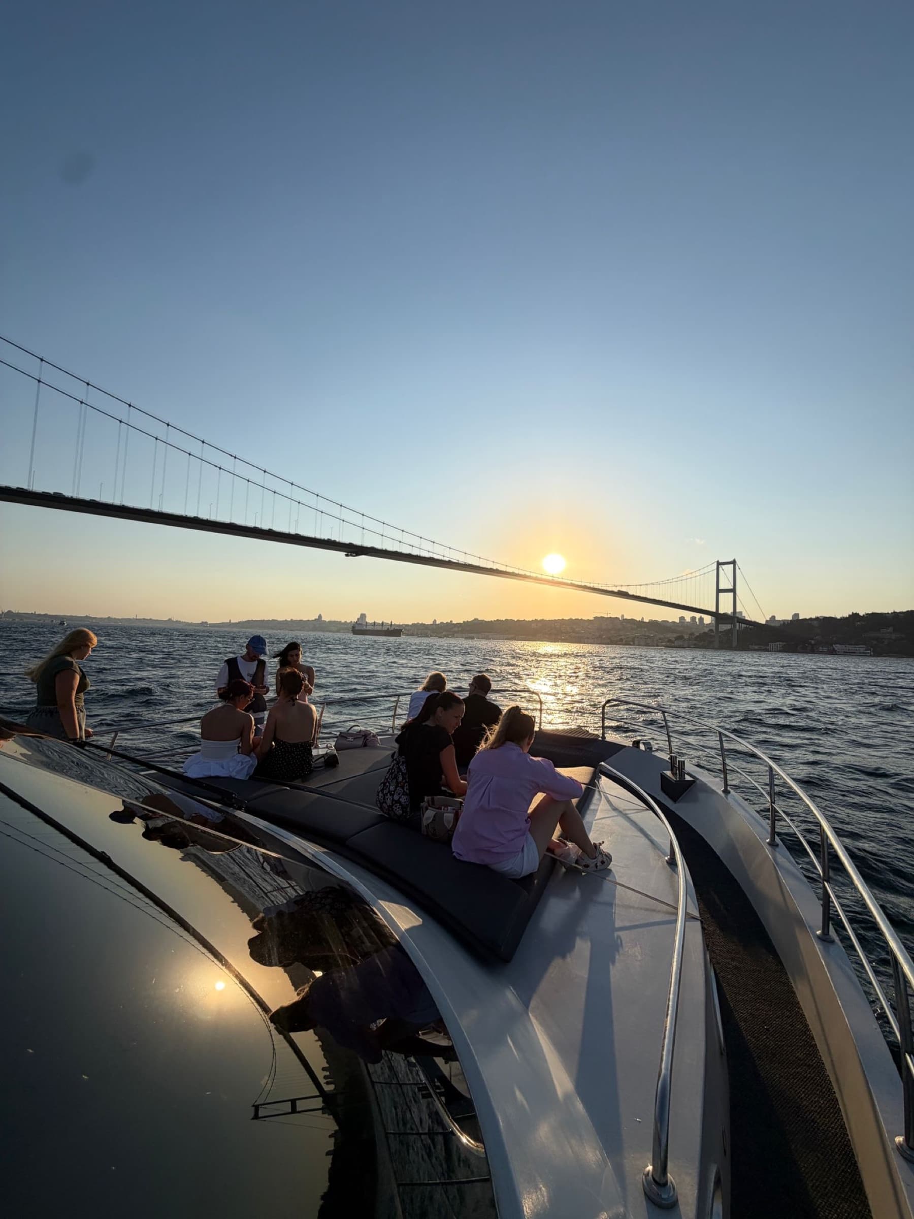 The sun dropping behind the bridge, guests on the bow
