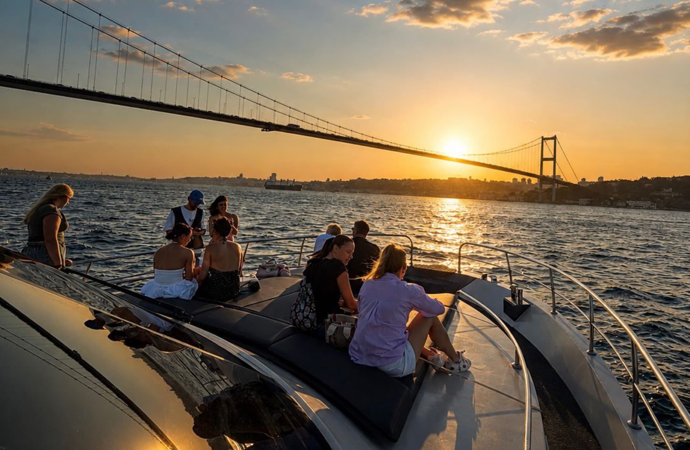 Guests on the foredeck under the bridge, evening light