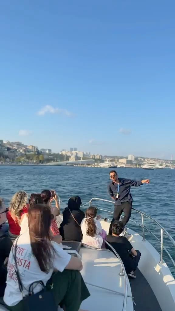 Guests on the bow at sunset under the Bosphorus Bridge, music playing